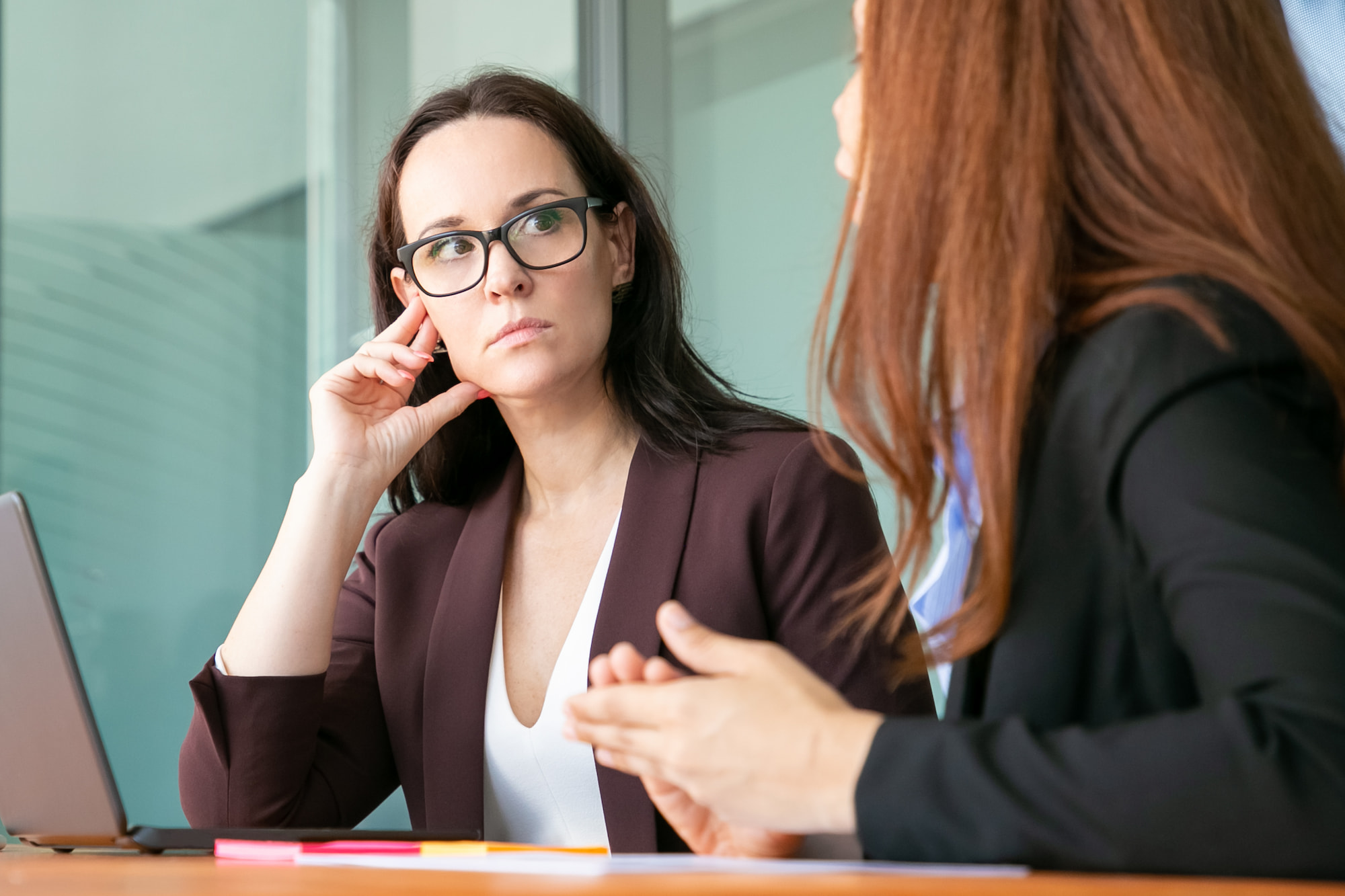 serious female professional wearing glasses office suit listening colleague corporate meeting 1
